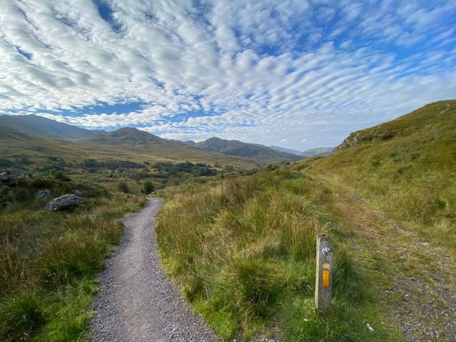 Crush stone trail, blue cloudy sky and the landscape filled with mountains.