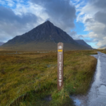 West Highland Way sign post, Buachaille Etive Mor, blue cloudy skies.