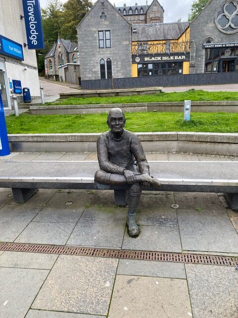 Statue of a man sitting on a bench rubbing his foot signifies the end of the West Highland Way.  Man with Sore Feet was made by David Annand.